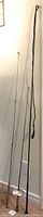 Fishing rod standing next to horse whip and fencing foil leaning against the wall.