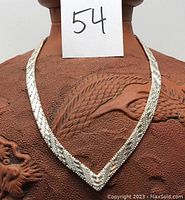 Front view of heavy sterling silver collar necklace displayed on a textured brown vase with dragon design.
