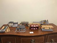 Photo showing full assortment of seven model buildings and station platforms arranged on wooden surface