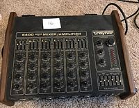 Top down front panel view showing six-input channel mixer/amplifier with individual volume, gain, bass, treble controls, master section with volume and equalizer, black metal panel with wooden side panels.