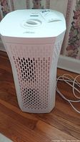 White Hunter air purifier with perforated front panel standing on wood floor.