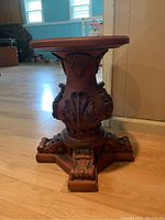 Side view of the round top plant stand showing carved leaf motifs and base detail