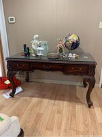 Full front view of carved wood table with decorative items on top