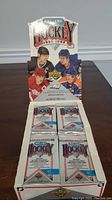 Open display box showing four unopened packs of 1991-1992 Upper Deck NHL hockey cards with player images on the box display.