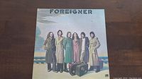 Front cover of Foreigner self-titled vinyl LP album showing band members standing on platform in coats with suitcases.
