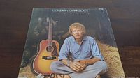 Front cover image of the Gordon Lightfoot Sundown vinyl LP album showing the artist sitting on hay with a guitar.