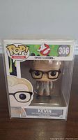 Front view of Kevin Ghostbusters Funko Pop figure in original box showing figure through clear window and box front artwork with number 306.