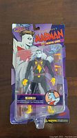 Front view of the Madman Black action figure in original blister packaging on wooden surface.
