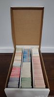 Photo showing a cardboard box filled with multiple stacks of monster trading cards sorted by color.