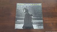 Front cover of Neil Young's 'After The Gold Rush' album showing Neil Young walking with a cat on his shoulder in front of a wire fence.