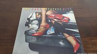Front cover of The Cars Greatest Hits vinyl album showing artistic car and legs image.