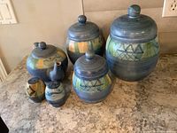 Full view of the set showing three canisters, teapot, and salt and pepper shakers arranged on a kitchen counter.