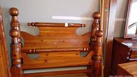 Front view of the wooden Cannon Ball style headboard and footboard with prominent rounded finial posts.