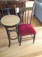 Photo showing the wooden plant stand with caned top alongside a wooden upholstered press back chair, both on hardwood floor.