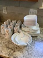 Mugs, plates, and bowls with floral design stacked and arranged on kitchen counter.