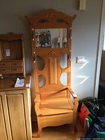 Full view of oak hall stand showing decorative carved top, mirror, coat hooks, and overall construction.