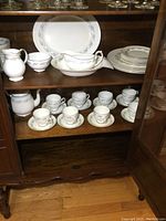 Complete Royal Grafton set displayed in wooden cabinet showing cups, saucers, platters, and serving items.