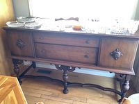 Front view of the sideboard showing two dovetail drawers in the center and cupboards on each side with decorative wood and metal knobs.