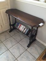 Front view of vintage wood sofa table showing tabletop and bottom book rack filled with books (not included in sale). Dark finish with visible wear.