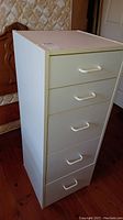 Front view of the laminated storage cabinet showing five drawers with white handles.