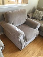 Front left angled view showing the chair’s rolled arm, cushioning, and fabric texture.