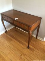 Full side perspective of vintage wooden desk showing queen anne style legs and top surface