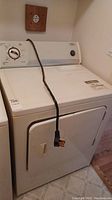 Front view of white Whirlpool electric dryer showing control dial, door, and power cord.