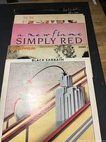 Five vintage vinyl LP records stacked showing album covers from Alice Cooper, Talk Talk, Simply Red, Led Zeppelin, and Black Sabbath.