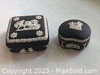 Two charcoal Wedgwood Jasperware trinket boxes side by side showing relief decoration