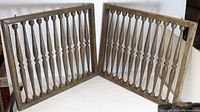 Two complete vintage turned wood framed window cover panels arranged in a corner showing vertical turned spindles inside the rectangular frame.