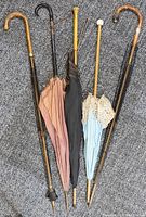 Full view of the 5 umbrellas showing various fabric canopies and handle shapes laid out on carpet.