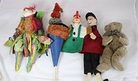 Five puppets and one plush teddy bear laid out in a row against a white background showing overall condition and colors