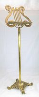 Full view of entire brass adjustable lyre music stand including lyre top, central column and base