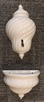 White ceramic holy water tank with swirl design and attached metal spout shown lying on carpet