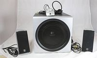 Front view of the complete Logitech speaker system including subwoofer, two satellite speakers, and wired controller.