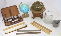 Full view of lot showing leather travel set, two globes, glass cookie jar, stone mortar and pestle, rulers and slide rule