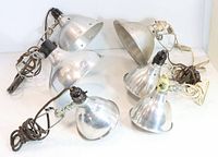 Five photo/work clip lamps with spun metal shades, cords coiled, arranged on white surface