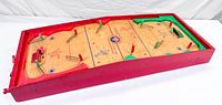 Full view of the wooden tabletop hockey game showing playing surface, pegs, frame, and central painted hockey rink design