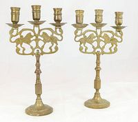 Pair of vintage brass candlesticks with double lion motif and round bases photographed against white background.