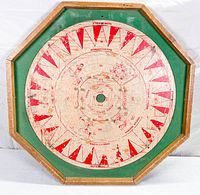 Front side of the octagonal game board featuring a red and white Crokinole game design with an octagonal wood frame and green trim, showing wear and paint flaking.