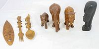 Full lot view showing all eight items: miniature mask, four salad servers (two forks, two spoons) with figurehead handles, three carved wooden elephants, and one black ceramic head.