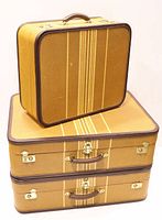 Three suitcases stacked showing gold/brown striped fabric, dark brown leather trim, gold-tone locks and handles.