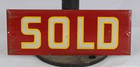 Front view of red metal rectangular sign with the word SOLD in yellow reflective letters and two mounting holes