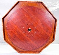 Front view of the octagonal wooden crokinole game board, showing the playing surface with circular scoring rings and center hole.