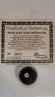 Certificate of Authenticity for the solid 14K gold miniature coin, indicating the coin number 24911 and authenticity details.