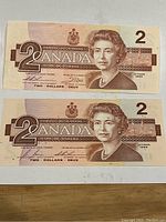 Front view of two 1986 Canadian $2 bills showing Queen Elizabeth II and denomination details.