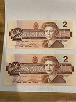 Front side of two 1986 Canadian two-dollar bills showing Queen Elizabeth II.