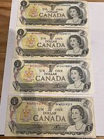 Front sides of four 1973 Canadian one dollar bills showing Queen Elizabeth II portraits and serial numbers.