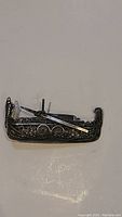 Close-up image of vintage silver gondola brooch showing intricate filigree design and attached oar.