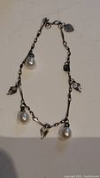 925 silver bracelet with three large white pearls and several silver leaf charms on a chain. The bracelet has a small heart-shaped tag near the clasp.